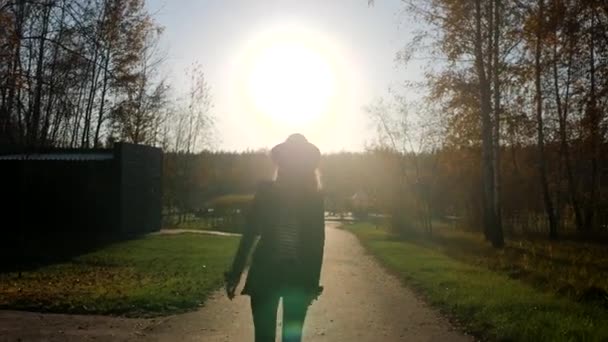 Silhoutter από μια κομψή γυναίκα yound περπατώντας μπροστά σε μια κάμερα στο πάρκο στο ηλιοβασίλεμα. Θαυμάζοντας την φύση το καλοκαίρι. — Αρχείο Βίντεο
