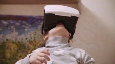 Yukarıya bakıyor ve sanal gerçeklik evde kapalı nesneleri dokunmak çalışırken Vr kulaklık, küçük kız.