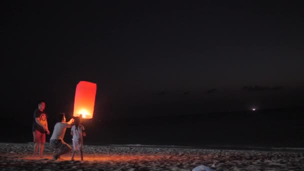 Phuket, Thajsko - 12 února 2019: Rodina spuštění sky papírové lucerny za soumraku na pláži — Stock video