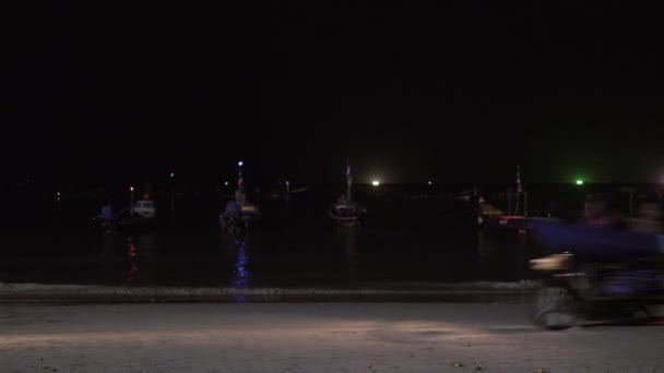 Neidentifikovaný rybářů na motorce jezdit po písku pláže před malým fisherboat v moři. Noční čas — Stock video