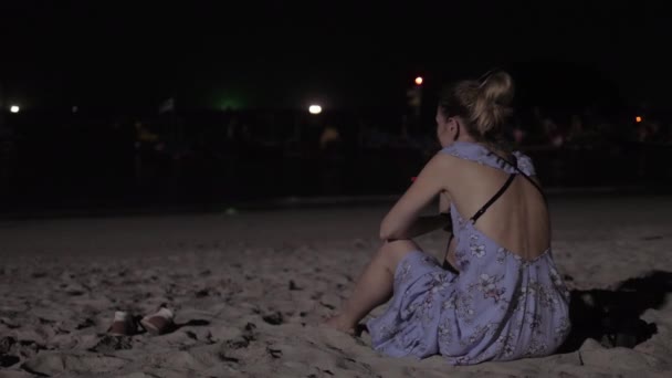 Mujer joven disfrutando del mar al atardecer. Sentado en la playa de arena. Mirando barcos de pesca. Tiempo nocturno — Vídeo de stock