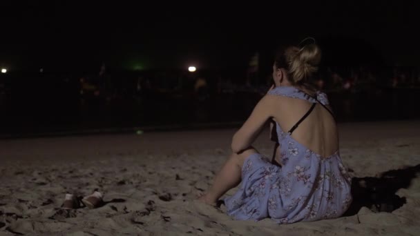 Giovane donna godendo il mare durante il tramonto. Seduto sulla spiaggia di sabbia. Guardando barche da pesca. Di notte — Video Stock