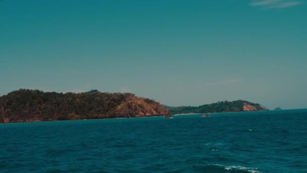 Море и остров в ясный день, вид с движущейся лодки — стоковое видео