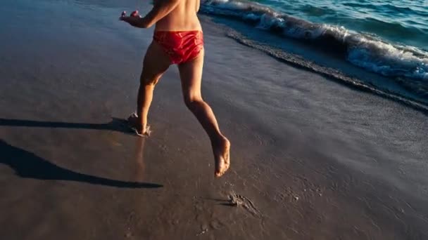 スローモーションで実行されている裸足少女の濡れた夜の太陽の暖かい光の海砂です。不注意な幸せな幼年期 — ストック動画