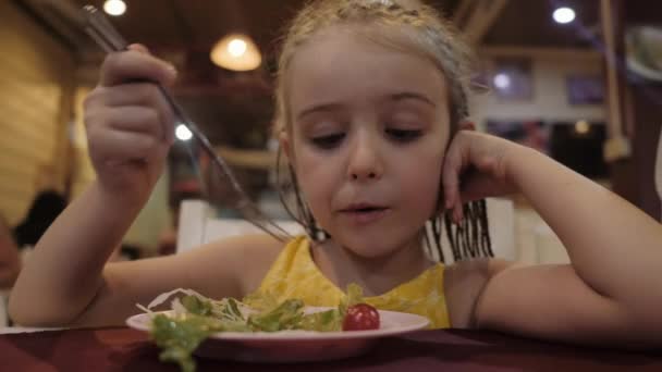 Kislány eszik zöld saláta étvágya az étteremben. Jó egészségi koncepció — Stock videók
