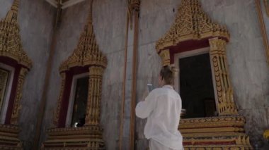 Genç turist kadın Tay Budist tapınağı cep telefonu ile fotoğraf yapma.