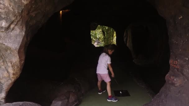 Lekfull barn dom. Liten flicka spela minigolf utomhus — Stockvideo