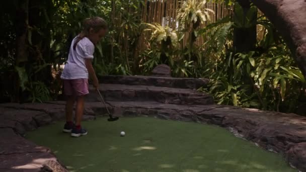 Infância Brincalhona. Menina jogar mini golfe ao ar livre — Vídeo de Stock