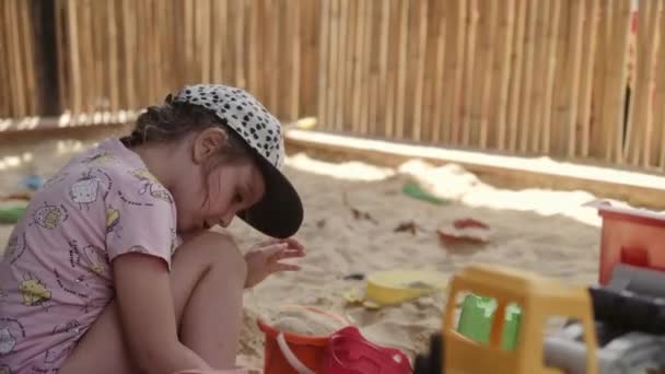 Маленькая девочка играет в песочнице с песком и игрушками — стоковое видео