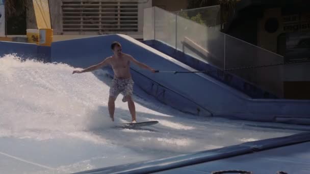 初心者ライダーは人工波でサーフィンに乗ることを学びます. — ストック動画