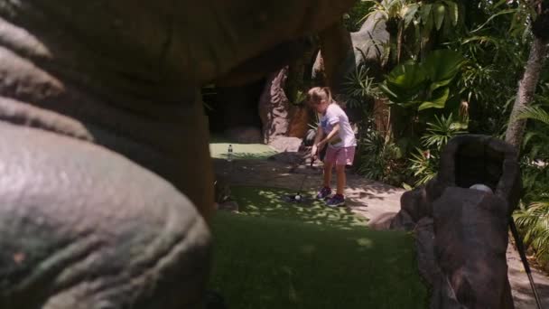 Speelse kindertijd. Klein meisje spelen mini golf buiten — Stockvideo