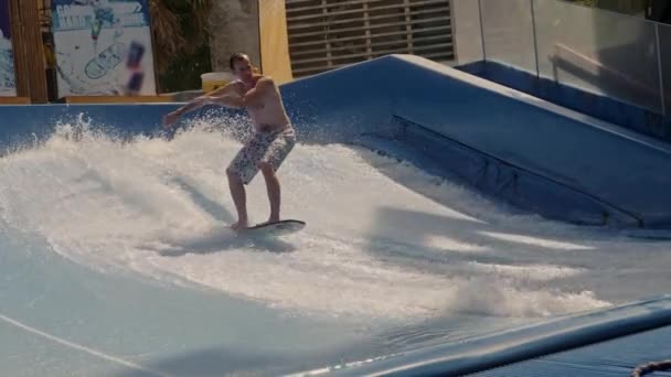 初心者ライダーは人工波でサーフィンに乗ることを学びます. — ストック動画