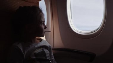 Uçakta pencereye bakan lolipop ile sevimli kız.