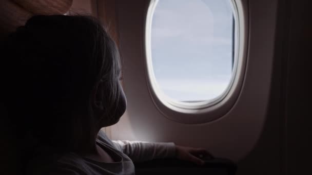 Süßes Mädchen mit Lutscher, das im Flugzeug aus dem Fenster schaut. — Stockvideo