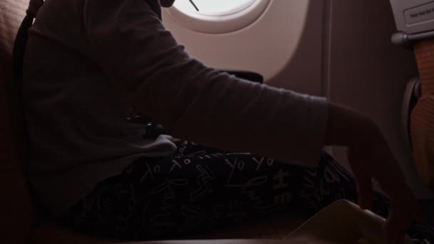Nahaufnahme einer Mädchenhände, die einen Sicherheitsgurt in einem Flugzeugstuhl anschnallt — Stockvideo