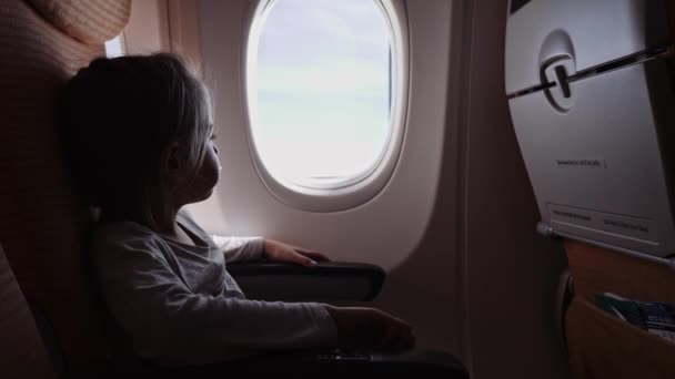 Linda chica con piruleta mirando a la ventana en el avión . — Vídeos de Stock