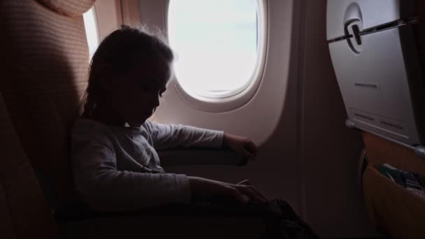 Linda chica con piruleta mirando a la ventana en el avión . — Vídeos de Stock