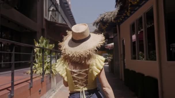 Hermosa mujer con sombrero de paja camina por la calle. Jugando a cámara . — Vídeos de Stock