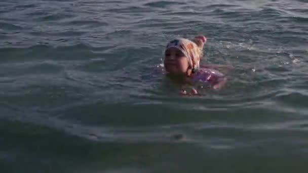 Маленькая девочка учится плавать в море — стоковое видео