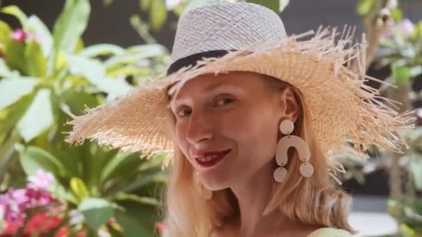 Портрет красивой молодой женщины в соломенной шляпе в солнечный день, смотрящей в камеру — стоковое видео