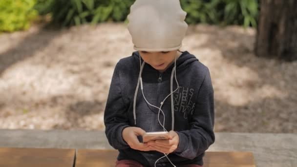 4K. Uma menina bonita curtindo música com telefone inteligente no parque — Vídeo de Stock