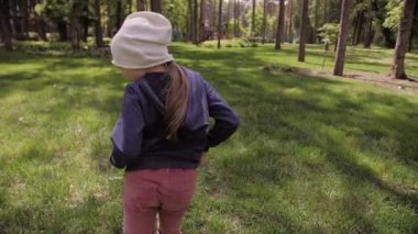 4K tasasız kız dans ediyor ve parktaki yeşil bir çayırda dönüyordu.