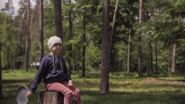 4K roztomilý dívka sedět na pařezu a hrát s frisbee. — Stock video