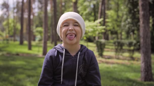 자극적 인 어린 소녀가 혀를 나타낸다. 공원의 여름 석양을 배경으로 한 클로즈업 사진. 건강 한 생활 방식 — 비디오