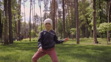 4K tasasız kız dans ediyor ve parktaki yeşil bir çayırda dönüyordu.