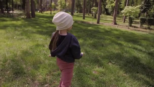 4K Fille insouciante dansant et tournant sur une prairie verte dans le parc en fin d'après-midi — Video