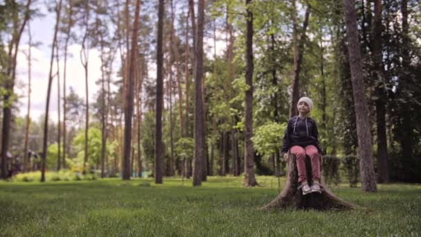 4K Gondtalan aranyos lány ül a fatönkön, és érezd jól magad. — Stock videók