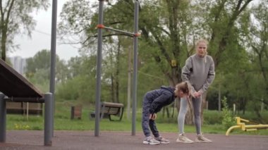 4K Anne ve Kızı açık hava sporları parkında alıştırma yapıyor.