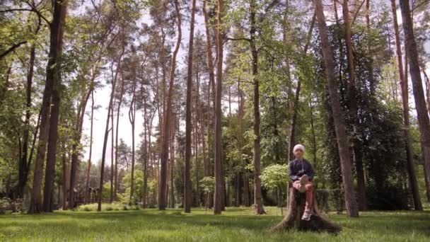 4K Безтурботний кучерява дівчина сидить на пеньку і отримує задоволення . — стокове відео