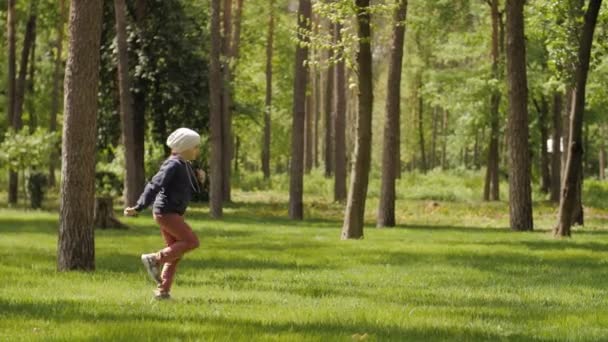 Happy childhood, cute girl happily run and jump through the forest park — Stok Video