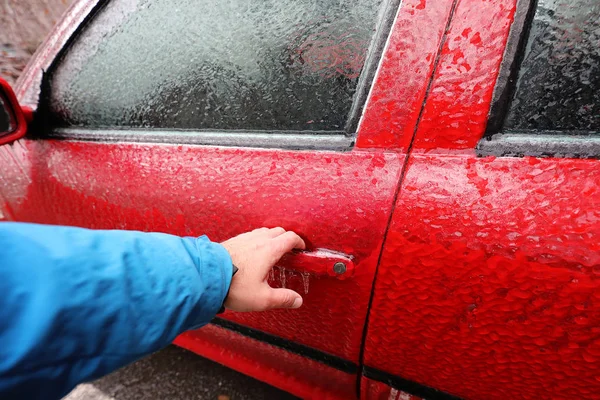 Transportation, winter, weather, vehicle concept. Hand on Car\'s door handle covered in snow and icy rain in winter. Blizzard Snowfall icy rain for weather concept