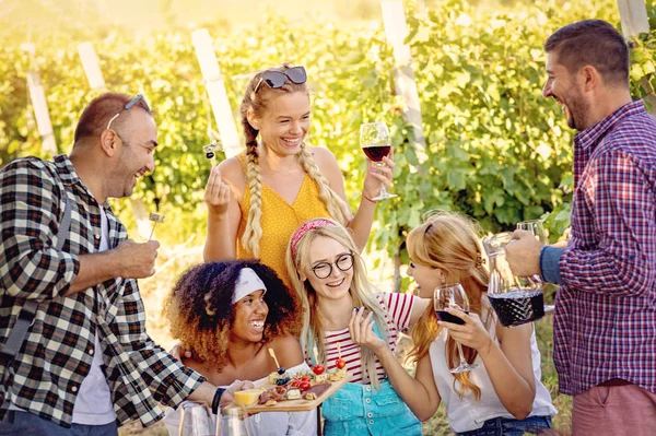 Happy friends tasting wine in vineyard - Young people enjoying time together outside at countryside - Youth friendship and wine tours concept