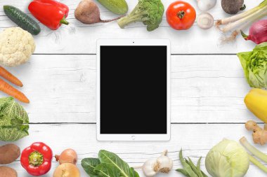 Tablet ve sebze wihite ahşap masa üzerinde. Üstten görünüm.