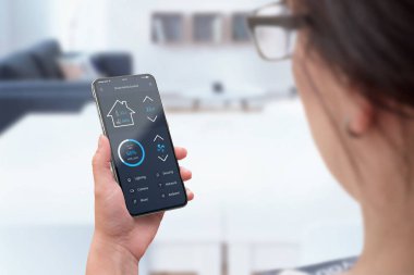 Kadın kullanımı modern akıllı telefon ile yuvarlak kenarları ve sıcaklık, ışık ve güvenlik izleme için akıllı ev kontrol app.