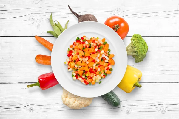 Chopped vegetables on plate. Fresh organic vegetables in plate background on white wooden cuisine table.