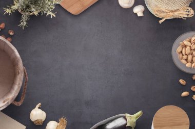 Malzemeler, süt kova, kesme tahtası, reçel kavanoz, baharat kutusu ve bitki yemek ile eski siyah mutfak masası. Boş alan orta.