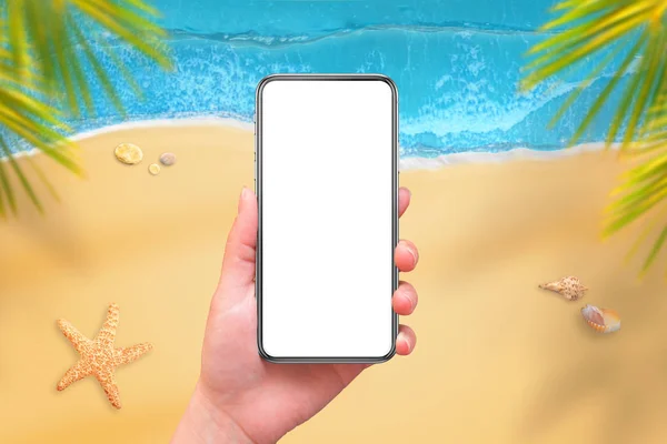 Mobile phone with isplated screen for mockup in woman hand. Beach and sea in background. Travel app design presentation.