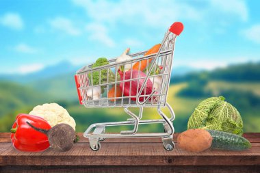 Bir tabloda bir arabası taze ve sağlıklı sebze ile arka planda bir kırsal.