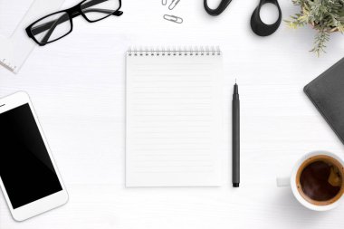 Boş defter kalem, bardak, fincan kahve, cep telefonu ile çevrili ofis masasında. Düz yatıyordu, en iyi görünümü.