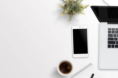 Beyaz masa metin için boş alan ile telefon ve dizüstü bilgisayar. Bitki, fincan kahve, Not defteri nad kalem. Düz yatıyordu kompozisyon.