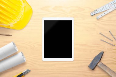 Mockup mimar masa için boş ekran ile tablet. Kask, araçları ve planları yanında. Üstten görünüm.