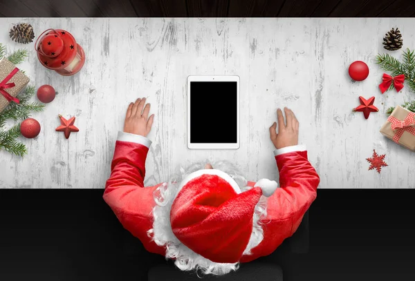 サンタ クロースの使用はモックアップ アプリ デザイン プレゼンテーションに空白の画面を搭載したタブレットします トップ ビューの横にあるクリスマスの装飾とシーン — ストック写真