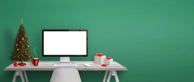 Bilgisayar masasında mockup Noel ağacı, hediyeler ve dekorasyon göster. Metin tebrik için yeşil duvar yanındaki boş alan.