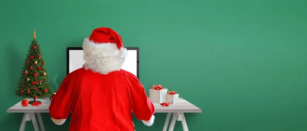 圣诞老人在网上寄信 办公桌上的圣诞树 礼物和装饰品 背景与复制空间的绿色墙壁 — 图库照片