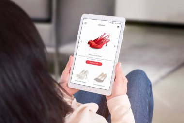 Sandalyeden tablet ile online alışveriş. Omzunun üzerinden görüntüleyin. Oturma odası iç arka planda.