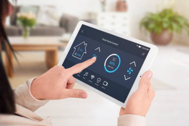 Modern yazılım tablet ekranda ev denetlemek için. Kadın kontrol sıcaklık oturma odasında. Yakın çekim.